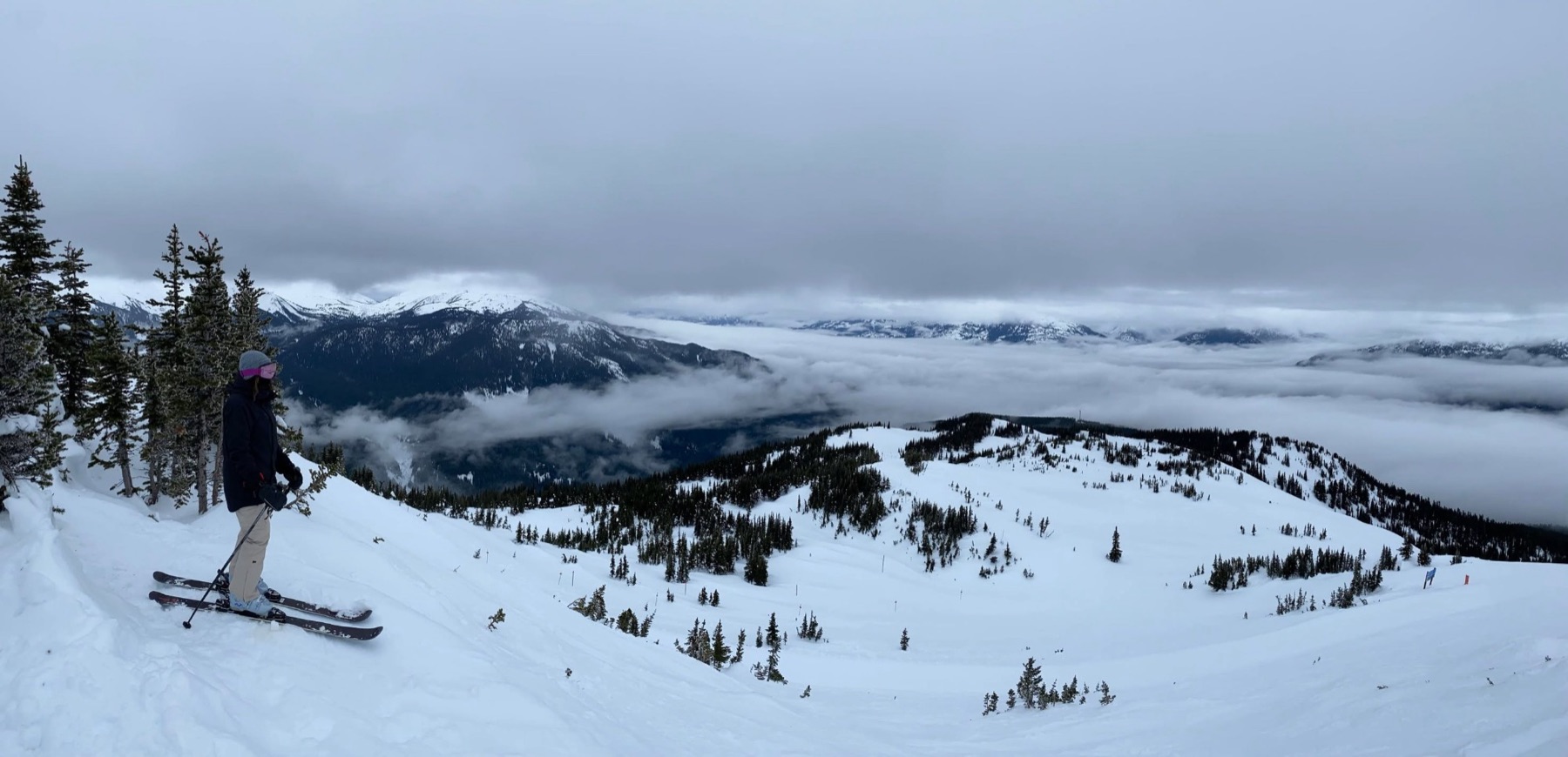 Une skieuse au sommet d'une montagne, au-dessus d'une mer de nuages